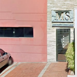 Na placa de alumínio, o nome do escritório de Botucatu/SP em letras vazadas se destaca na parede de pedras.