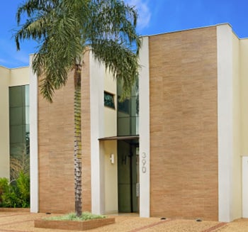 No escritório em Ribeirão Preto/SP, os tons claros da fachada trazem suavidade e harmonia com o jardim bem cuidado.  