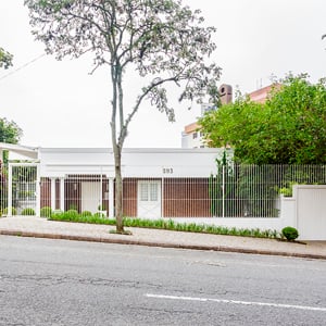 Localizada no coração do Centro Cívico em Curitiba, próximo ao TJ/PR, a fachada da banca de estilo inglês, com suas colunas e linhas retas, harmoniza-se com o jardim frontal.