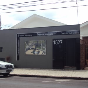 Na fachada do escritório de Franca/SP, a placa espelhada desfoca todo o movimento da rua. 