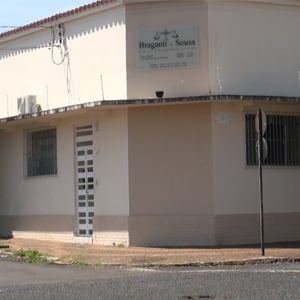 A luz do sol ilumina a frente da fachada de Araguari/MG, evidenciando a cor neutra do escritório.