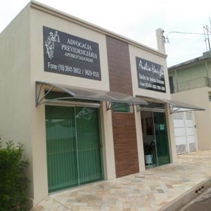 A calçada de pedras se contrapõe à faixa amadeirada decorativa da fachada do escritório de Junqueirópolis/SP. 