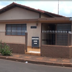 Na varanda da casa de esquina de Guará/SP, uma flecha em uma placa indica a direção do escritório.