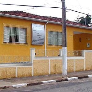 A parede mostarda sustenta o painel prateado de identificação da banca mineira de Guaxupé/MG. 