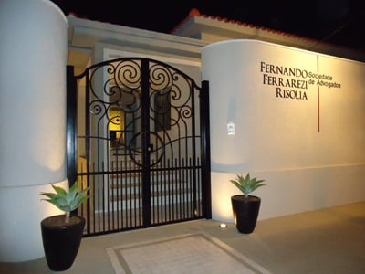 O letreiro da banca se destaca juntamente com as luzes e o portão do escritório em São Paulo/SP.