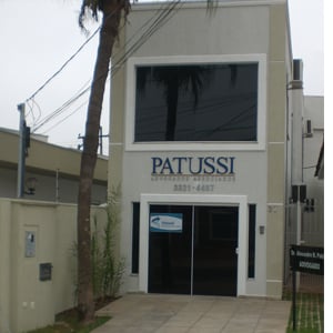 No escritório de Campo Grande/MS, o alto coqueiro se enquadra no vidro fumê da banca. 