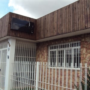 As ripas de madeira no alto da fachada do escritório de Franca/SP contrastam com a parede de pedras. 