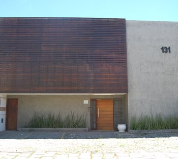 As ripas de madeira no alto da fachada contrastam com a parede de concreto e as plantas harmonizam a entrada do escritório em Salvador/BA.