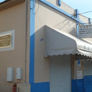 Na lateral do cartório de Pacaembu/SP, uma placa de metal e vidro indica a presença do escritório de advocacia. 