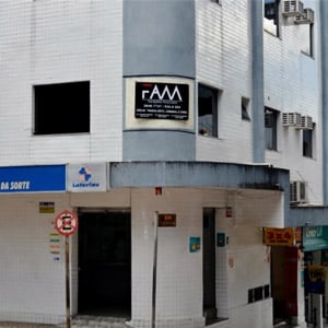 A placa do escritório de Coronel Fabriciano/MG se destaca na parece revestida de pequenos azulejos brancos. 