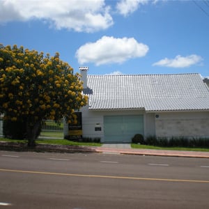 Em São Miguel do Oeste/SC, a árvore florida em amarelo vibrante harmoniza com a placa que identifica o escritório, adequando-se inclusive às cores da logomarca. 