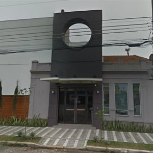 Com uma arquitetura diferenciada, o escritório sulista de Pelotas é circundado por um verde canteiro e uma calçada de faixas brancas e cinzas.